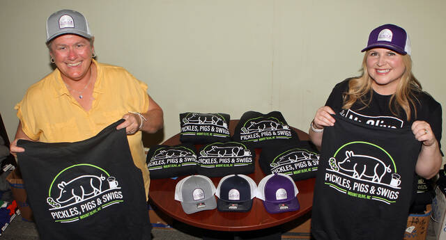 130105874_web1_PPS-merch
Mount Olive Area Chamber of Commerce President Julie Beck, left, and Melissa Kirkpatrick, with the Mt. Olive Pickle Co., show off the Pickles Pigs & Swigs sweatshirt hoodies and caps that will be on sale during the third annual festival to be held Saturday, Nov. 11 at the Southern Bank Parklet. The festival features a barbecue cook-off, barbecue plate sales, craft beer, free Mt. Olive Pickles, vendors and other activities. (Steve Herring|mountolivetribune.com)