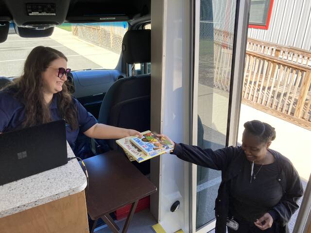 130977474_web1_dudley-mobile-library-1
Natasha Robinson, right, returns books to Susan Masuda, who is manning the circulation desk in the Sprinter van that houses the mobile library for the Wayne County Public Library system. The mobile library visits the WAGES Stephen and Susan Parr Family Learning Center in Dudley every other Wednesday, 9:30-11 a.m. Robinson checked out these books two weeks prior, to read to the two- and three-year-old children she teaches at the Center. (Kathy Grant Westbrook|mountolivetribune.com)
