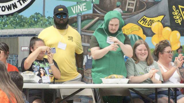 131473502_web1_festival1
A festive atmosphere filled the air as a costumed pickle and a contestant in a bright yellow shirt celebrated the start of the pickle eating contest.