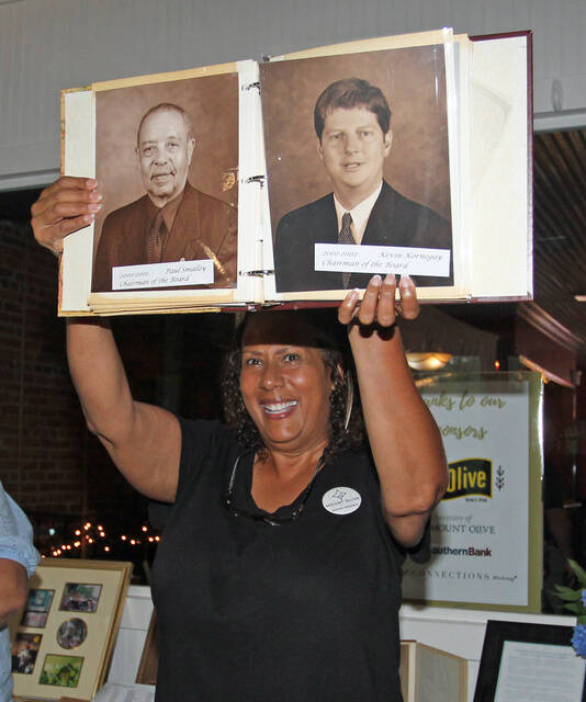 131567663_web1_aChamber-Pernell
Pernell Brickey holds up a photo album featuring a photo of her father, Paul Smalley, left, whom she credited with getting her involved with the Mount Olive Area Chamber of Commerce. She shared her story Thursday night during the Chambers 95th anniversary celebration at Ribeyes Steakhouse. (Steve Herring|mountolivetribune.com)