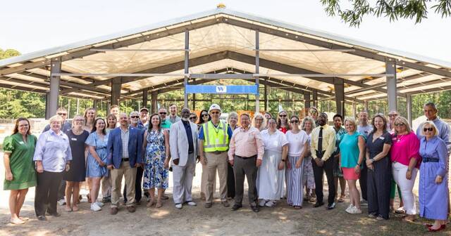 WCC administrators, board members, faculty, and staff stand in front of the blue beam installed at the agriculture buildings topping out ceremony. (WCC photo)