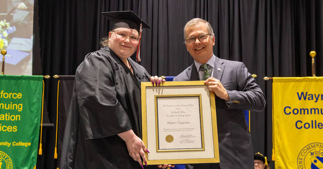 WCC Simulation and Game Development Instructor Cheyenne Prybylinski (left) receives the 2026 George E. Wilson Excellence in Teaching Award from Foundation of WCC Board Chair Scott Newton (right) during WCCs spring commencement ceremony. (WCC photo)